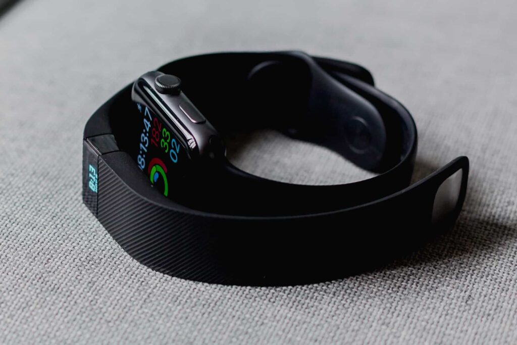 Close-up of a smartwatch with a colorful digital display on a black band resting on a light-gray fabric surface.