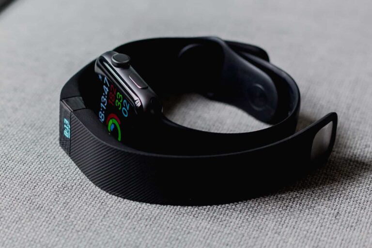 Close-up of a smartwatch with a colorful digital display on a black band resting on a light-gray fabric surface.