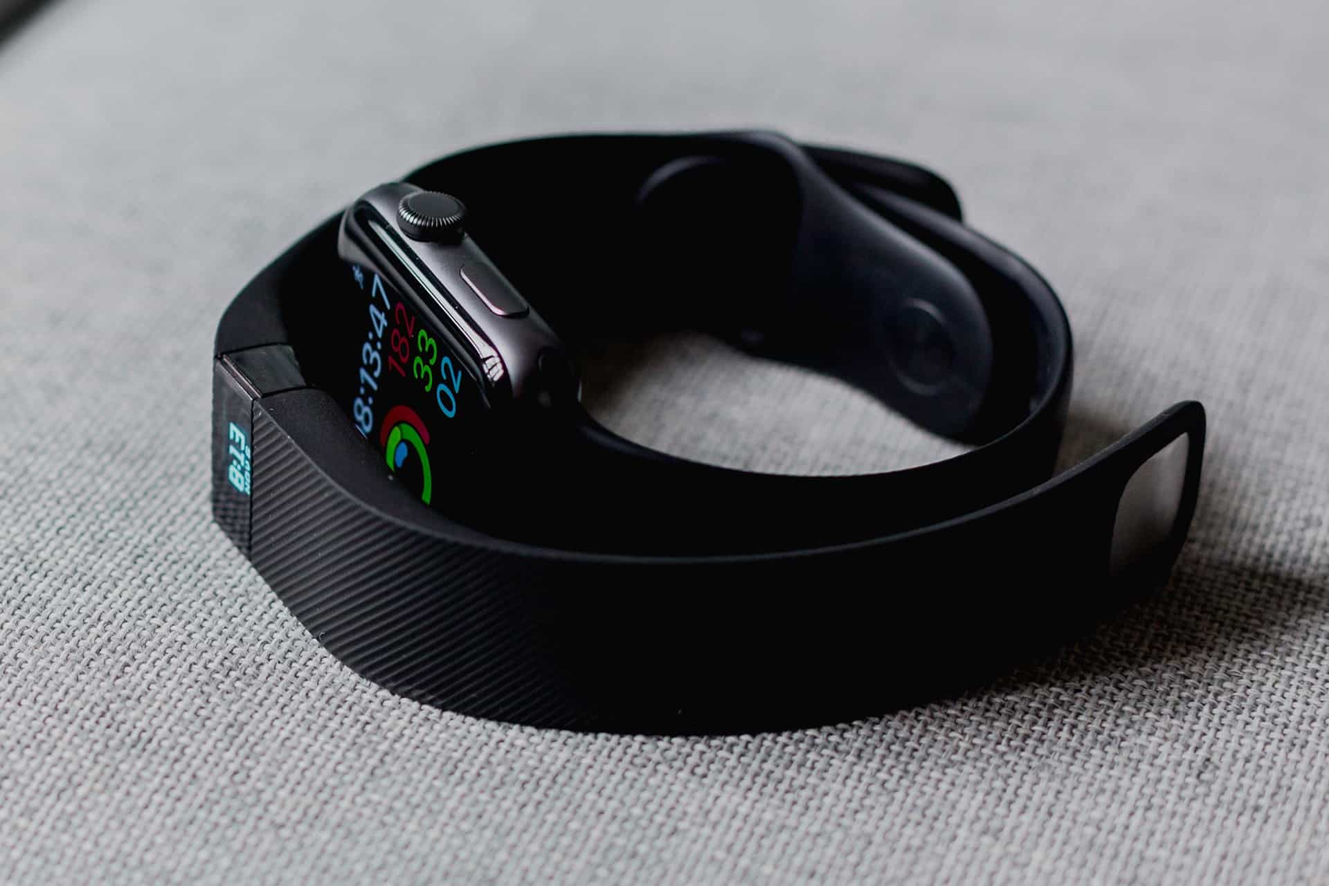 Close-up of a smartwatch with a colorful digital display on a black band resting on a light-gray fabric surface.
